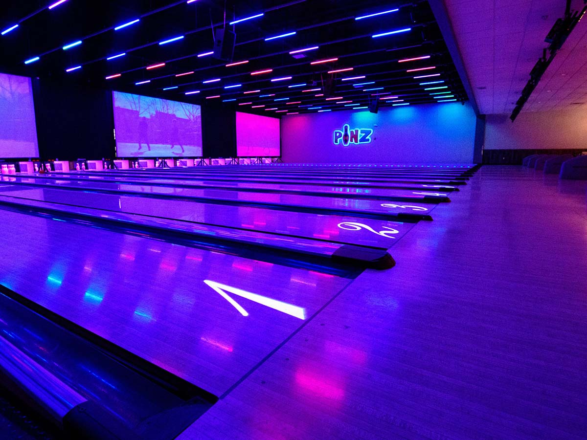 Projection screens and lighting fixtures over bowling lanes